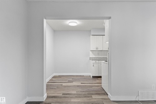 Archway entry to a space featuring wood-finish flooring and a ceiling-mounted light fixture - #9 14230 80 St Nw, Edmonton, AB - Indoor Photo Showing Other Room