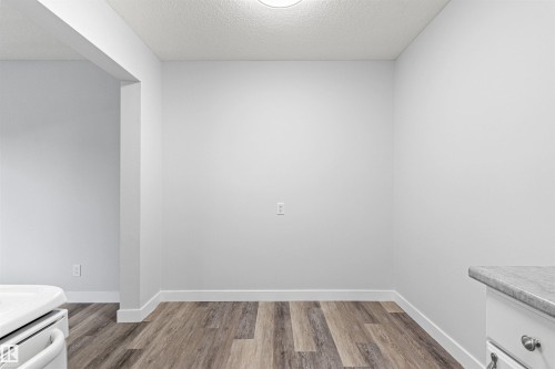 Bright, open room featuring wood-finish flooring, clean white walls, recessed ceiling lighting, and a corner powder room with chrome fixtures - #9 14230 80 St Nw, Edmonton, AB - Indoor Photo Showing Other Room