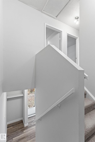 Carpeted staircase with wall-mounted handrail, leading to an upper landing with two doorways and overhead lighting - #9 14230 80 St Nw, Edmonton, AB - Indoor Photo Showing Other Room