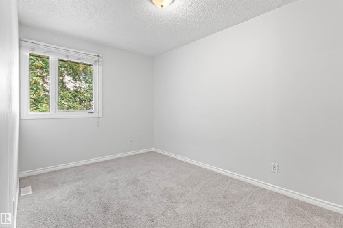 Neutral wall color with plush carpet flooring, trimmed window, and overhead lighting - #9 14230 80 St Nw, Edmonton, AB - Indoor Photo Showing Other Room