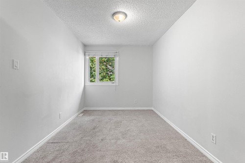 Bright secondary bedroom featuring neutral carpet flooring, white walls, and a recessed ceiling light - #9 14230 80 St Nw, Edmonton, AB - Indoor Photo Showing Other Room