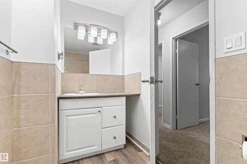 Vanity with integrated sink, contemporary vanity lighting, and wall-mounted mirror - #9 14230 80 St Nw, Edmonton, AB - Indoor Photo Showing Bathroom