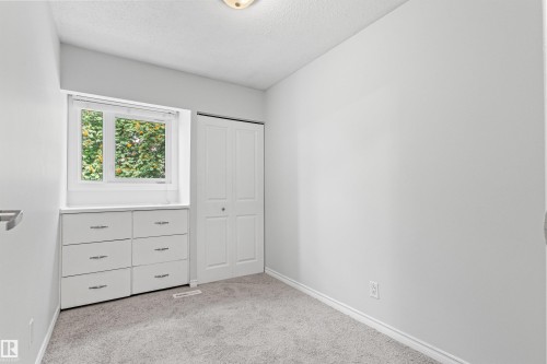 Neutral wall color, carpet flooring, built-in window storage, bifold closet doors, and a ceiling-mounted light fixture - #9 14230 80 St Nw, Edmonton, AB - Indoor