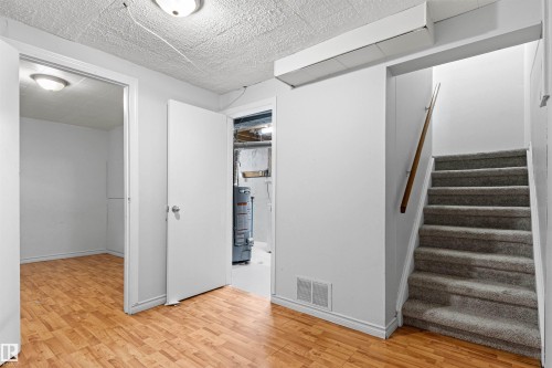 Wood-finish flooring, white walls, overhead ceiling lights, and carpeted stairs with a wood handrail - #9 14230 80 St Nw, Edmonton, AB - Indoor Photo Showing Other Room