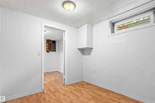 Wood-finish flooring with white wall paneling - #9 14230 80 St Nw, Edmonton, AB - Indoor Photo Showing Other Room