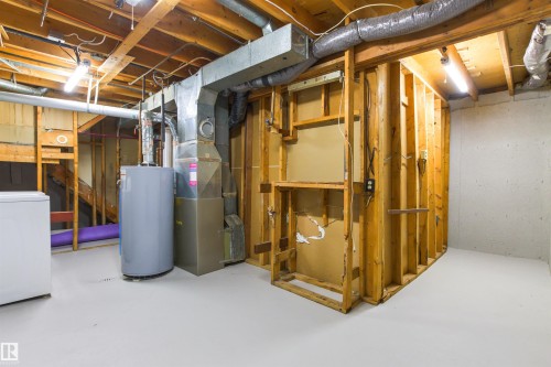 Unfinished basement with exposed wood framing, concrete foundation walls, and a water heater and furnace installation - #9 14230 80 St Nw, Edmonton, AB - Indoor Photo Showing Basement