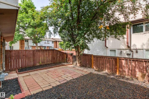 Expansive backyard retreat featuring brick and gravel hardscaping, wooden privacy fencing, and mature shade trees - #9 14230 80 St Nw, Edmonton, AB - Outdoor