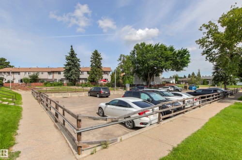 Paved parking area bordered by wooden fencing and a concrete path - #9 14230 80 St Nw, Edmonton, AB - Outdoor