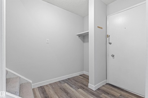 Entryway featuring wood-finish flooring, a built-in coat rack, and an integrated storage shelf - #9 14230 80 St Nw, Edmonton, AB - Indoor