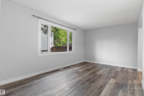 Wood-finish flooring with white trim, large window with white frame, and light gray walls - #9 14230 80 St Nw, Edmonton, AB - Indoor Photo Showing Other Room