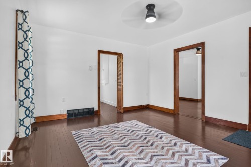 Spacious foyer showcasing rich wood-finish flooring, multiple doorway entries, and abundant natural light from ceiling-mounted fixture - 9921 109 Street, Fort Saskatchewan, AB - Indoor Photo Showing Bedroom