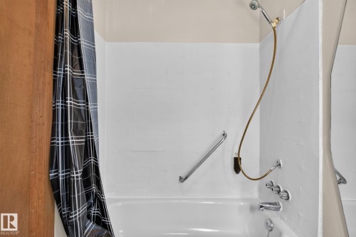 White tub with chrome fixtures and grab bar - 9921 109 Street, Fort Saskatchewan, AB - Indoor Photo Showing Bathroom