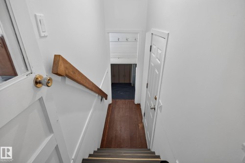 Wood handrail, paneled interior door, wood-finish flooring, white walls - 9921 109 Street, Fort Saskatchewan, AB - Indoor Photo Showing Other Room