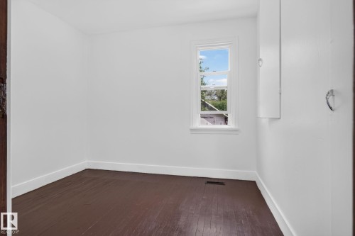 Painted wood flooring, white walls, built-in wall storage, and a single window - 9921 109 Street, Fort Saskatchewan, AB - Indoor Photo Showing Other Room