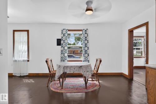 Bright interior with white walls, dark wood-finish flooring, and natural wood trim around windows and doorways - 9921 109 Street, Fort Saskatchewan, AB - Indoor Photo Showing Dining Room