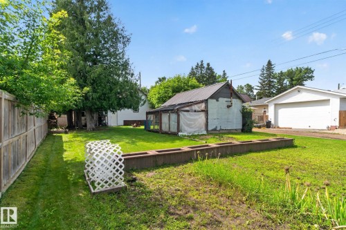 Expansive backyard featuring a privacy fence, established trees, and a detached outbuilding - 9921 109 Street, Fort Saskatchewan, AB - Outdoor With Backyard
