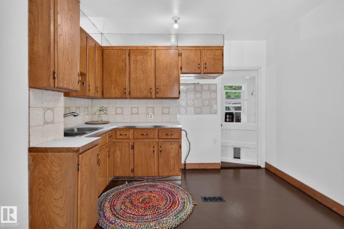 Wood-finish cabinetry, tile backsplash, laminate countertops, and a stainless steel sink - 9921 109 Street, Fort Saskatchewan, AB - Indoor Photo Showing Kitchen With Double Sink
