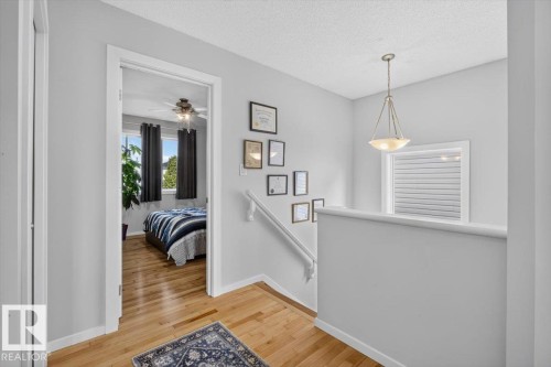Bright hallway with wood-finish flooring, crisp white walls, and architectural interest created by framed wall décor - 722 88A Street Sw, Edmonton, AB - Indoor Photo Showing Other Room