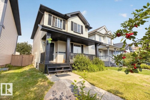 Two-story exterior with light-colored siding, dark trim, and a covered front porch featuring dark columns and railings - 722 88A Street Sw, Edmonton, AB - Outdoor With Deck Patio Veranda