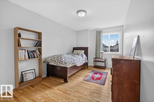 Hardwood flooring, light gray wall finishes, a built-in bookshelf, and a window with natural light - 722 88A Street Sw, Edmonton, AB - Indoor Photo Showing Bedroom