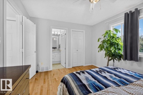 Bright, airy bedroom featuring warm wood-finish flooring, white six-panel doors, and abundant natural light from multiple windows - 722 88A Street Sw, Edmonton, AB - Indoor Photo Showing Bedroom