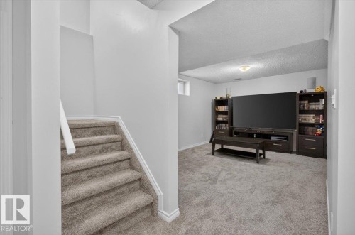 Finished basement recreation room featuring neutral carpet flooring, recessed ceiling lighting, and built-in dark wood cabinetry with integrated media shelving - 722 88A Street Sw, Edmonton, AB - Indoor Photo Showing Other Room