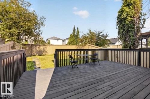 Expansive composite deck with horizontal board decking and black aluminum railing, overlooking a large, level lawn framed by mature trees and established landscaping - 722 88A Street Sw, Edmonton, AB - Outdoor With Deck Patio Veranda
