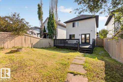 Expansive backyard featuring a wood privacy fence, concrete stepping stones, and a built-in fire pit - 722 88A Street Sw, Edmonton, AB - Outdoor