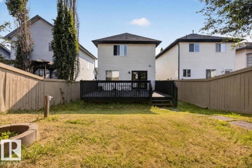 Fenced backyard featuring a wood deck with steps, a concrete block fire pit, and a grass area - 722 88A Street Sw, Edmonton, AB - Outdoor