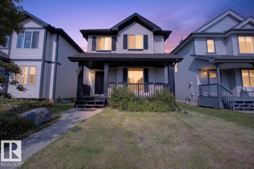 Two-story exterior with light-colored siding, contrasting dark trim, a covered front porch, and a concrete front path - 722 88A Street Sw, Edmonton, AB - Outdoor With Deck Patio Veranda With Facade