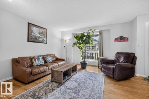 Bright living area with wood-finish flooring, light grey walls, a large window, and recessed ceiling lighting - 722 88A Street Sw, Edmonton, AB - Indoor Photo Showing Living Room