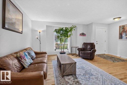 Wood-finish flooring, white painted walls, and a large window providing natural light - 722 88A Street Sw, Edmonton, AB - Indoor Photo Showing Living Room