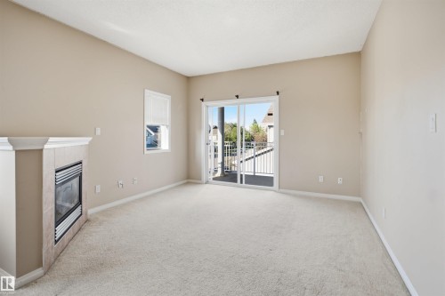 Spacious room featuring neutral paint tones and light-toned carpeting - #95 3040 Spence Wd Sw, Edmonton, AB - Indoor With Fireplace