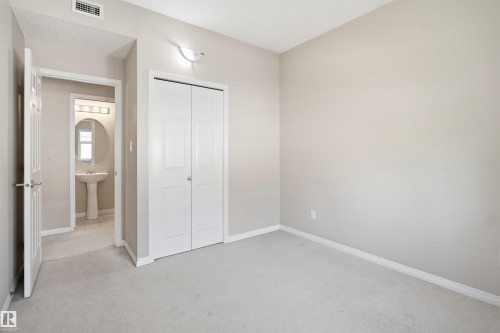 Carpeted interior space featuring neutral wall tones, white trim, and a bi-fold closet with paneled doors - #95 3040 Spence Wd Sw, Edmonton, AB - Indoor Photo Showing Other Room
