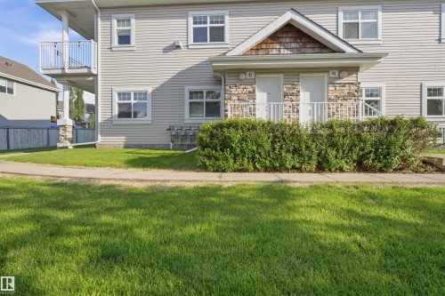 Multi-family property exterior with light-colored siding and stone accents - #95 3040 Spence Wd Sw, Edmonton, AB - Outdoor