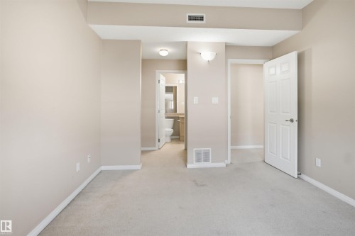 Carpeted interior space with neutral wall tones and white baseboards - #95 3040 Spence Wd Sw, Edmonton, AB - Indoor Photo Showing Other Room