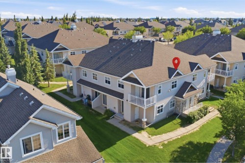 Multi-story townhouse featuring light-colored siding, a dark shingled roof, and white-railed balconies - #95 3040 Spence Wd Sw, Edmonton, AB - Outdoor With Deck Patio Veranda