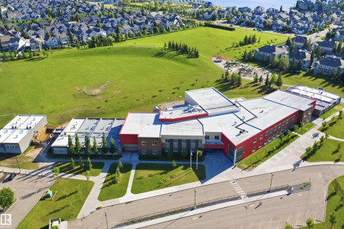 Modern educational facility featuring a large green space, sports field, and a contemporary architectural design - #95 3040 Spence Wd Sw, Edmonton, AB - Outdoor With View
