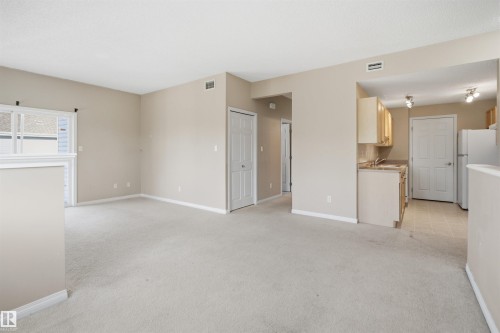 Spacious living area with neutral carpeting, painted walls, and white trim - #95 3040 Spence Wd Sw, Edmonton, AB - Indoor Photo Showing Kitchen