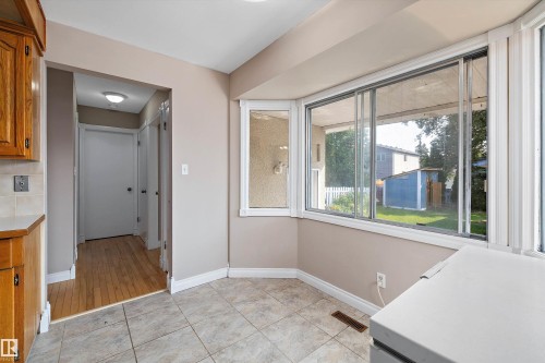Bright kitchen and dining area featuring expansive multi-pane windows overlooking the backyard, wood-finish cabinetry, and abundant natural light from corner window placement - 3511 73 Street Nw, Edmonton, AB 