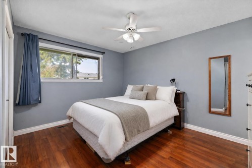 Wood-finish flooring, ceiling fan with integrated lighting, and a window offering natural illumination - 3511 73 Street Nw, Edmonton, AB 