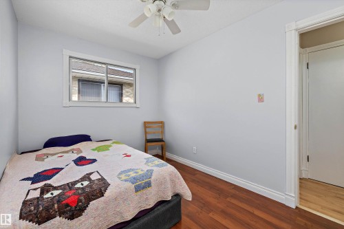 Bright bedroom with hardwood flooring, ceiling fan, and large double-hung window providing natural light - 3511 73 Street Nw, Edmonton, AB - Indoor Photo Showing Bedroom