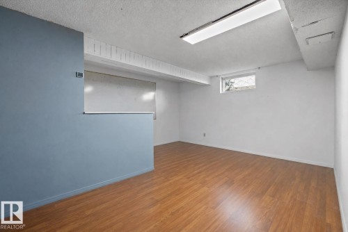 Wood-finish flooring, white painted walls, and a partial partition wall - 3511 73 Street Nw, Edmonton, AB 