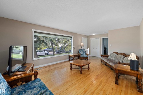 Spacious living room featuring hardwood flooring, large picture window with natural light, and multiple functional areas for entertaining and relaxation - 3511 73 Street Nw, Edmonton, AB 