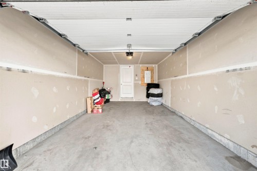 Spacious two-car garage featuring a concrete floor, an overhead door with a track system, and an interior access door - 1172 Aster Boulevard Nw Nw, Edmonton, AB - Indoor Photo Showing Garage