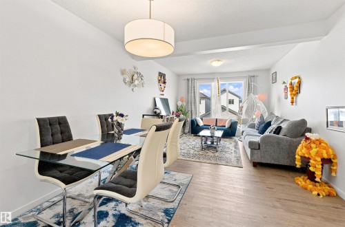 Open-concept living and dining area featuring light wood-finish flooring, a contemporary drum pendant light, and recessed ceiling lighting - 1172 Aster Boulevard Nw Nw, Edmonton, AB - Indoor
