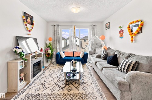 Living area featuring wood-finish flooring, light-colored walls, and a window with vertical blinds - 1172 Aster Boulevard Nw Nw, Edmonton, AB - Indoor Photo Showing Living Room