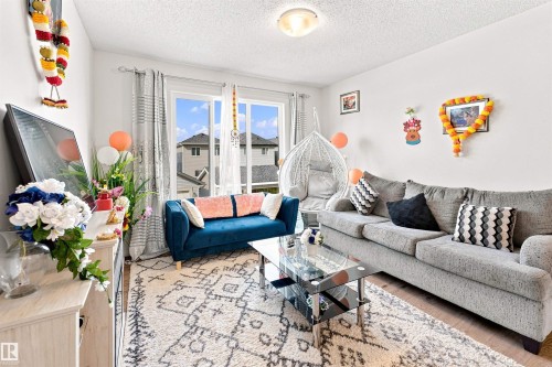Bright living area featuring wood-finish flooring and a textured ceiling - 1172 Aster Boulevard Nw Nw, Edmonton, AB - Indoor Photo Showing Living Room