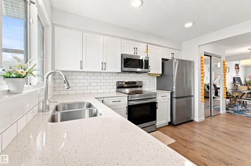 Modern kitchen featuring light-toned countertops, white subway tile backsplash, and stainless steel appliances - 1172 Aster Boulevard Nw Nw, Edmonton, AB - Indoor Photo Showing Kitchen With Stainless Steel Kitchen With Double Sink