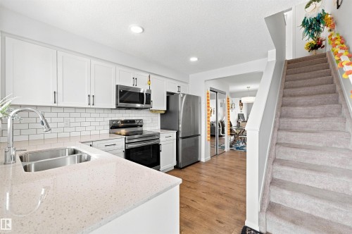 Modern kitchen featuring white shaker cabinetry, stainless steel appliances, a subway tile backsplash, and light-toned countertops - 1172 Aster Boulevard Nw Nw, Edmonton, AB - Indoor Photo Showing Kitchen With Stainless Steel Kitchen With Double Sink With Upgraded Kitchen
